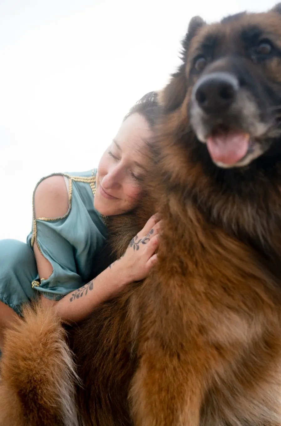 A woman in green cuddling a large fluffy German shepherd