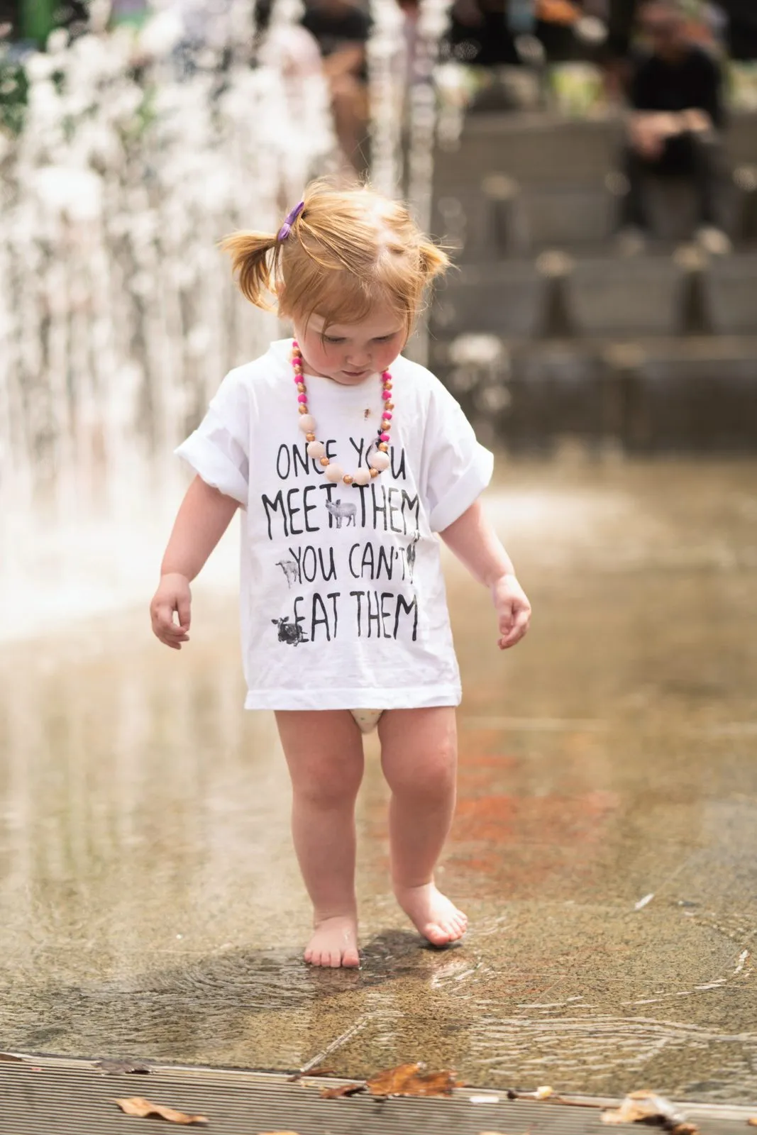 A toddler in an oversized T-shirt paddling through a fountain at a festival, Adelaide