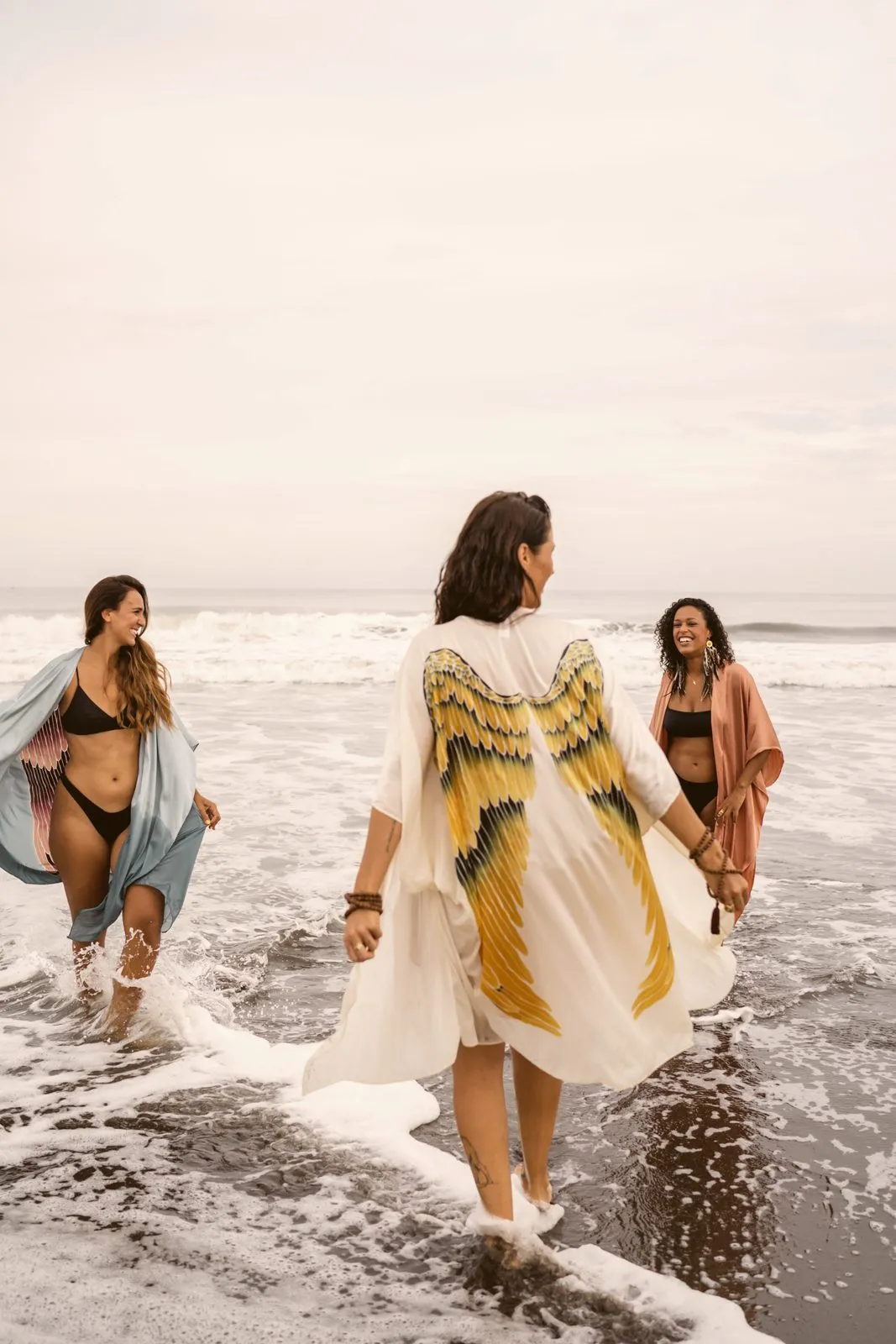 Three women in winged kimonos walking through the shallows, Warriors of the Divine