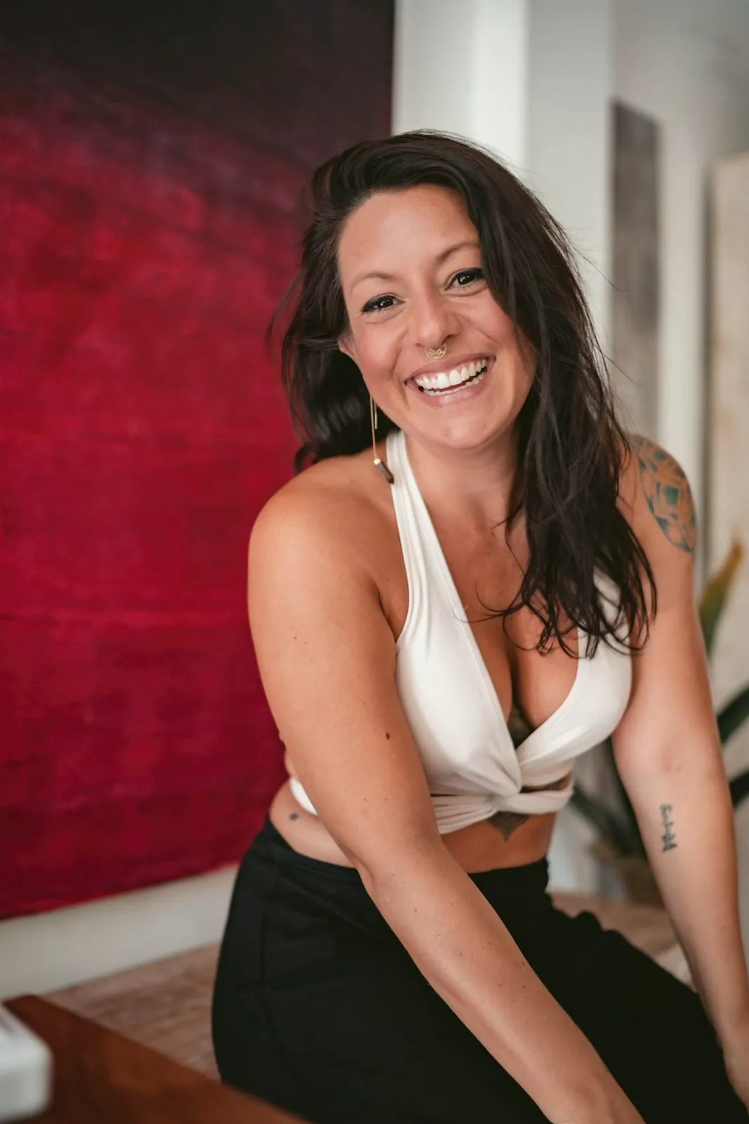 A laughing woman in a white crop top against a red painted wall