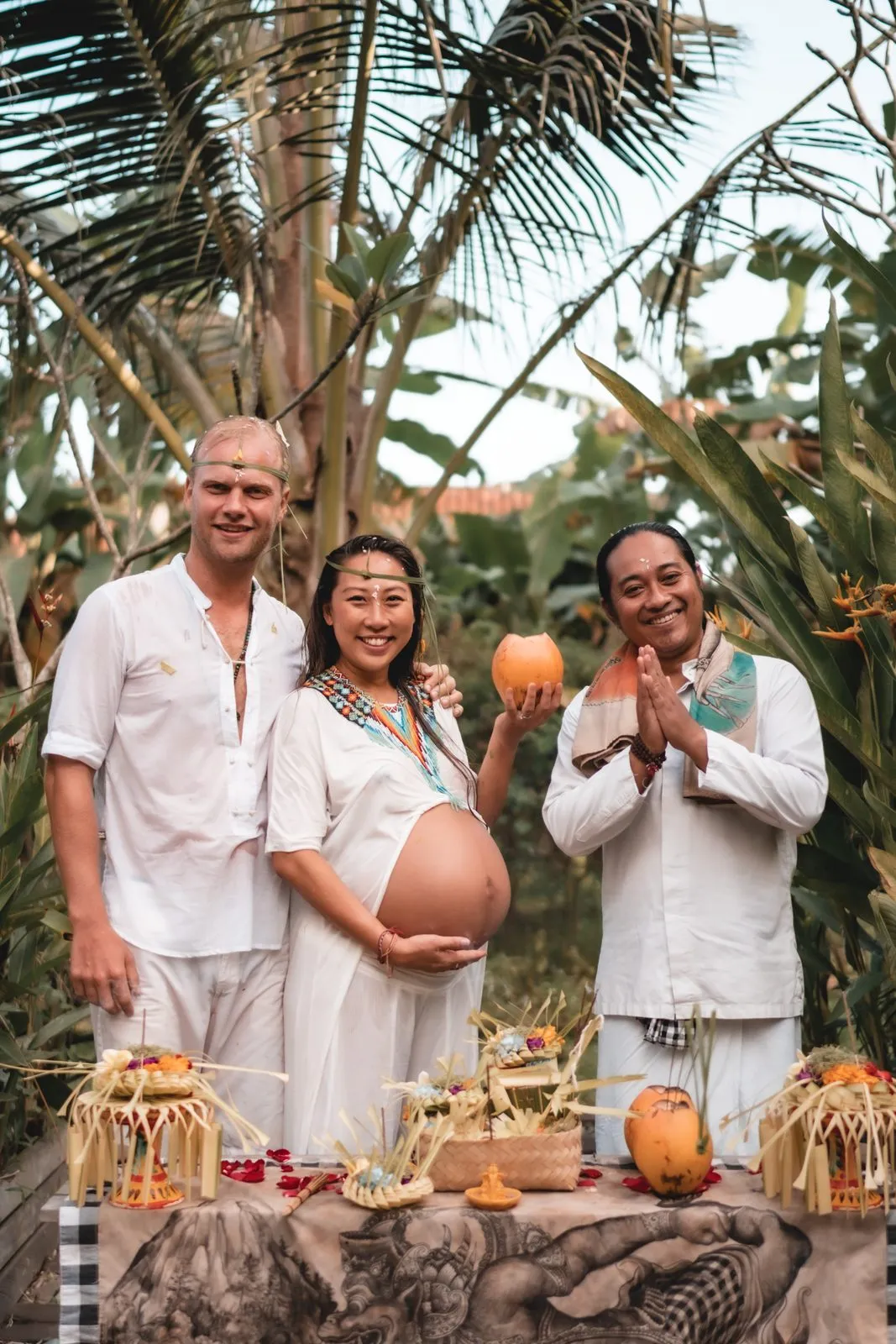 An expectant couple at a Balinese blessingway with the priest beside them, offerings on the table