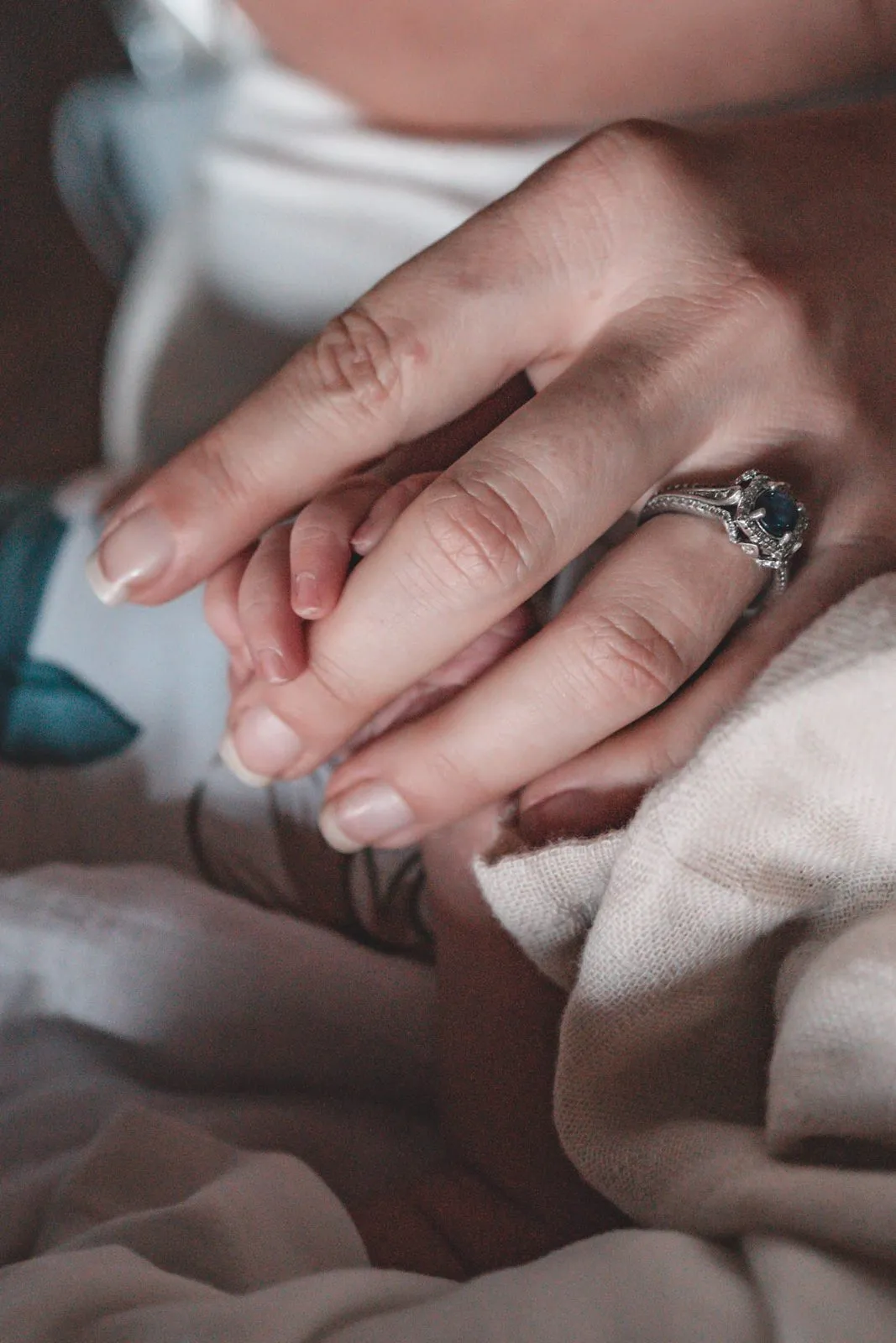 A newborn's hand wrapped around a mother's finger, close up