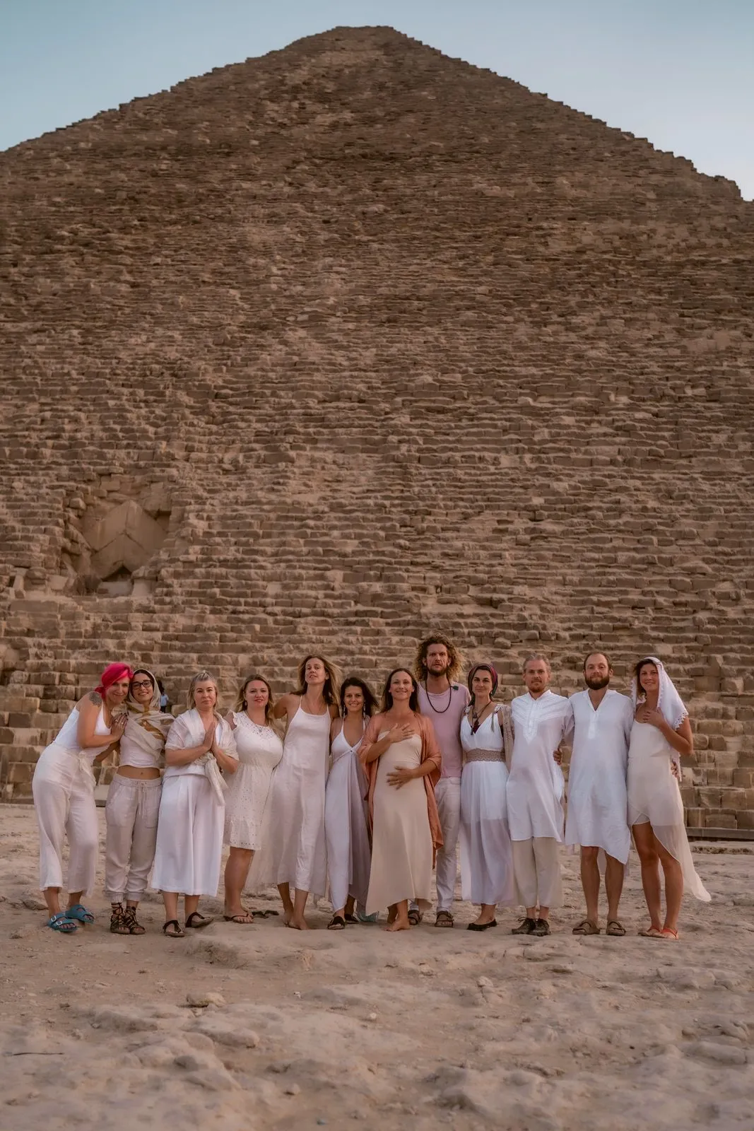 A retreat group in white standing together at the base of the Great Pyramid, Giza