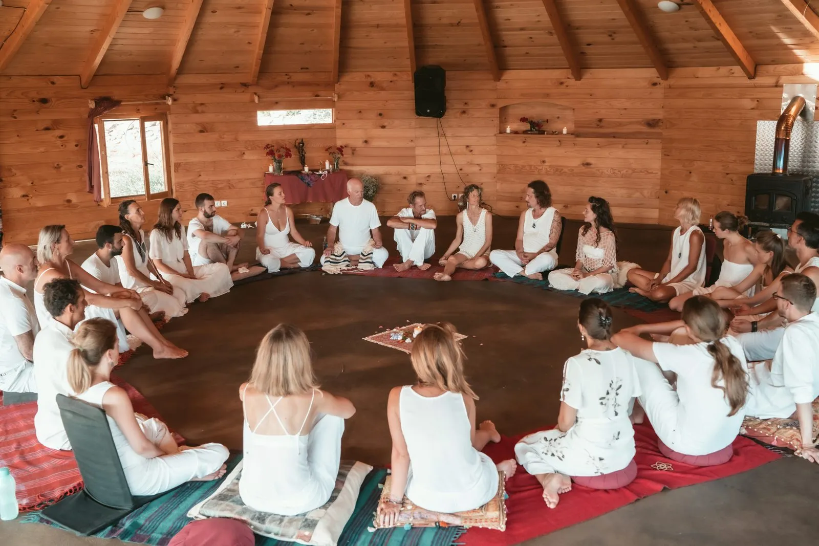 A retreat group seated in a wide circle on the floor of a timber hall, sharing