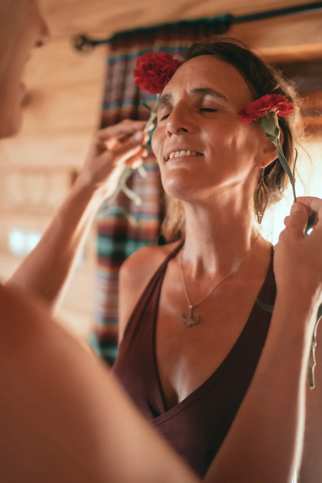 A woman with her eyes closed having a red flower tucked into her hair, on retreat