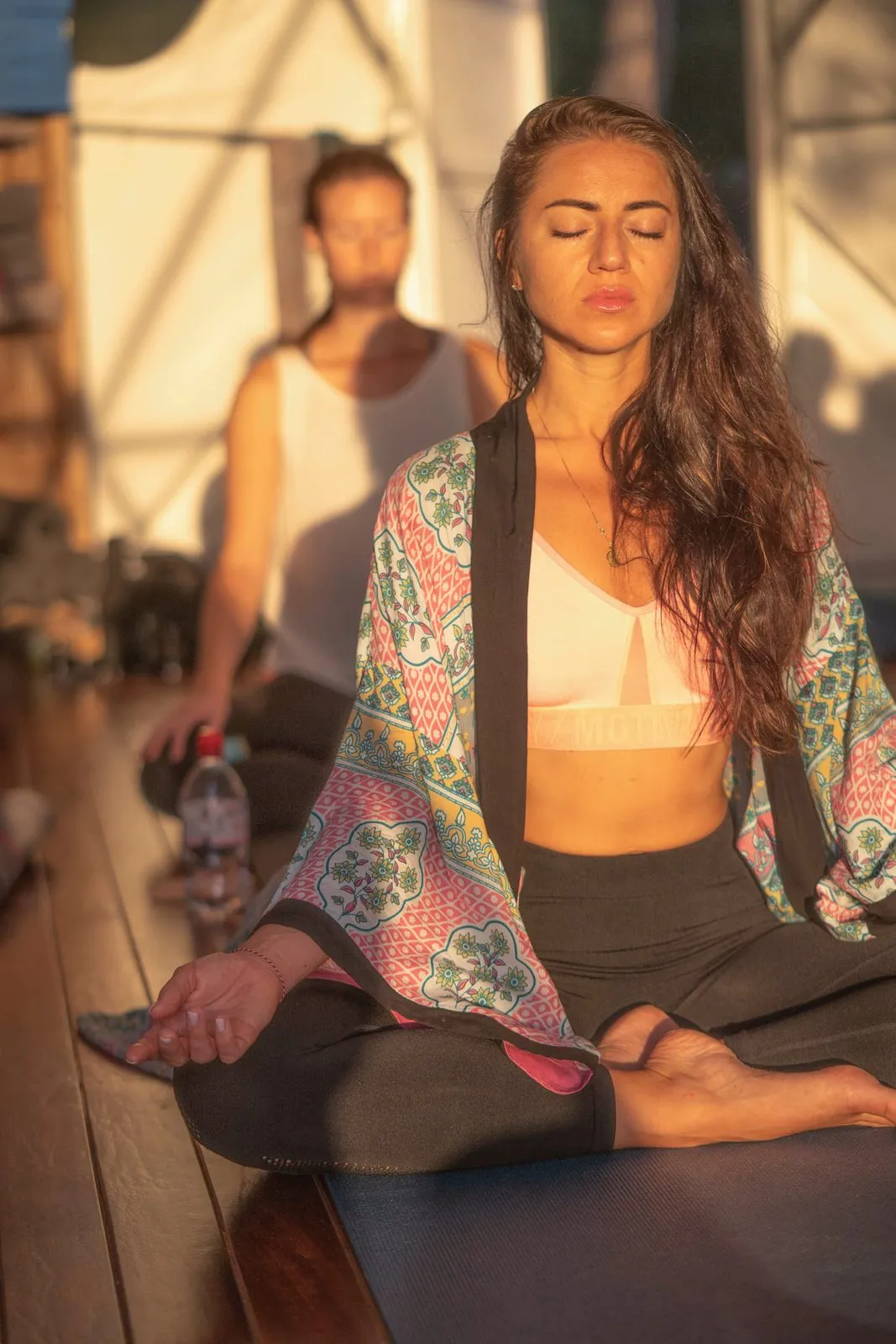 A woman in a patterned kimono meditating in a dome at sunset, others seated behind her, Ibiza
